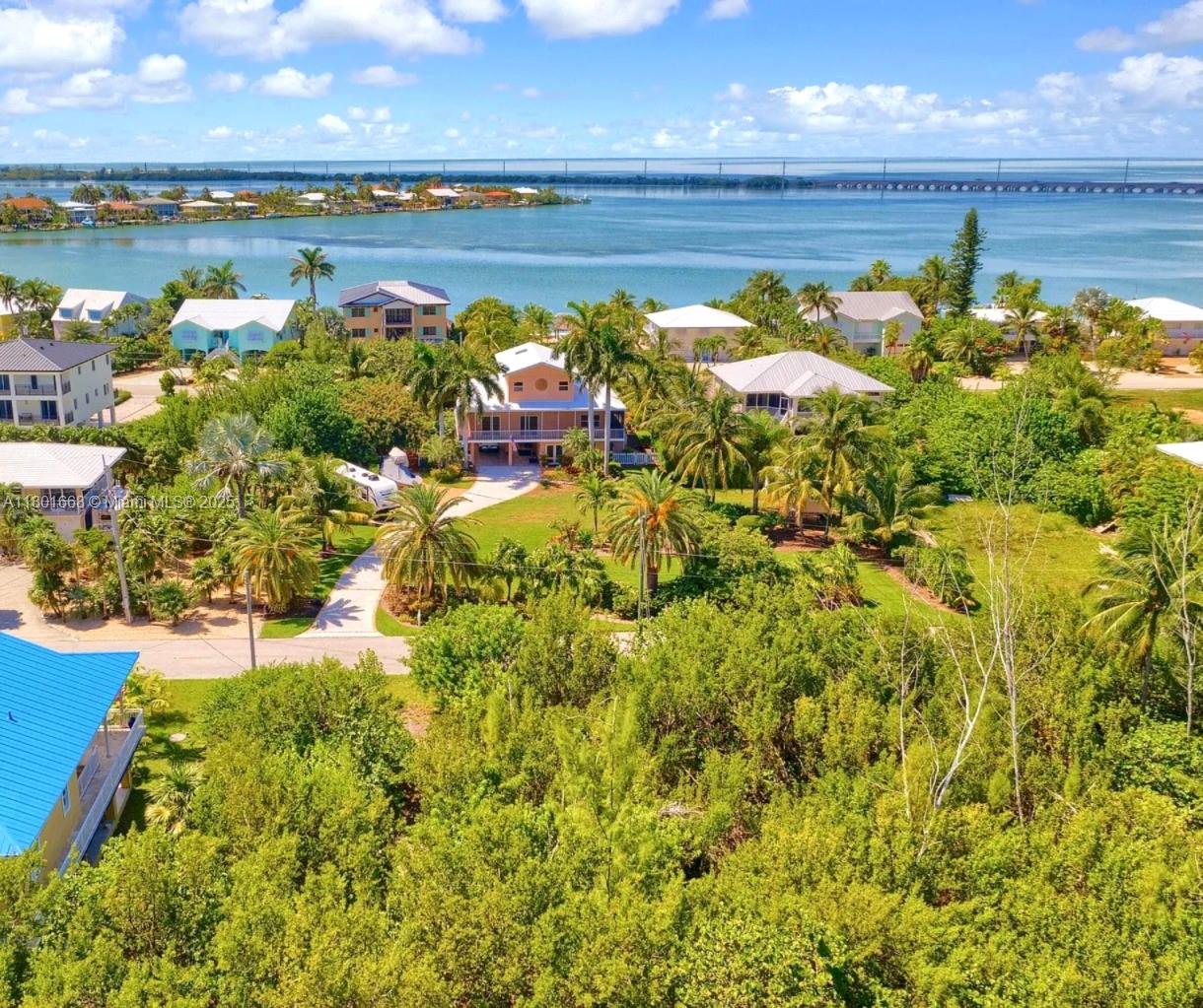 An aerial view shows several houses surrounded by lush tropical vegetation near a coastal waterway — 111 Jamaica St, Duck FL 33050, DUCK, FL