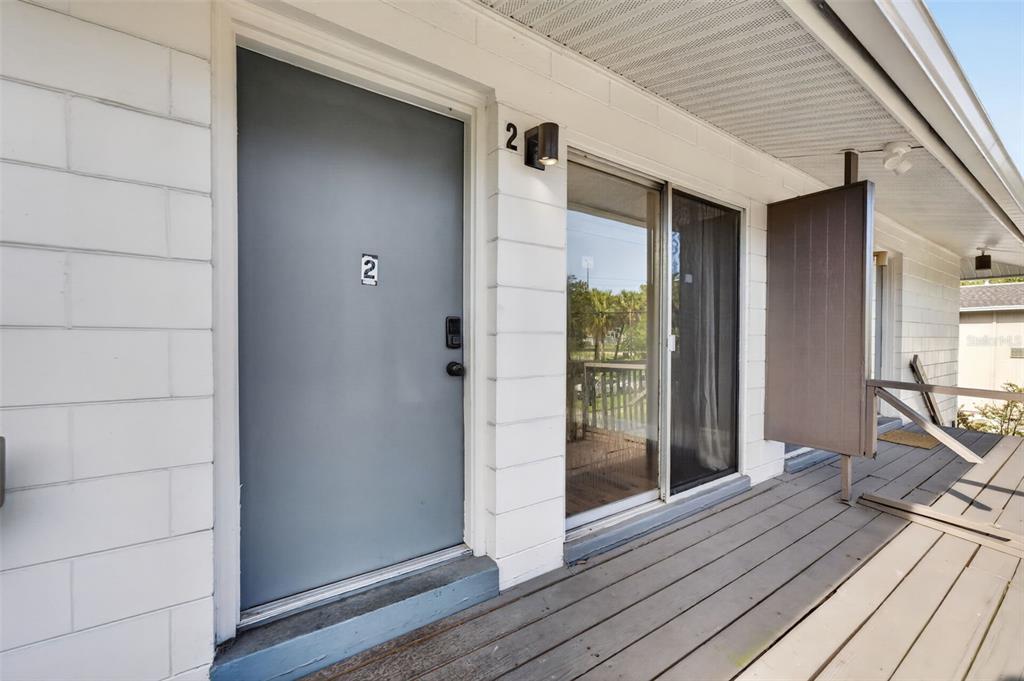 A gray door and sliding glass door are on a wooden deck of a building — 118 W AMERICA STREET UNIT 2, ORLANDO, FL