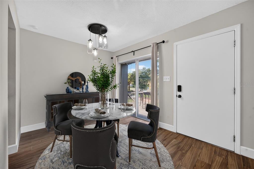 A dining room features a round marble table, four upholstered chairs, and a sliding glass door — 118 W AMERICA STREET UNIT 2, ORLANDO, FL