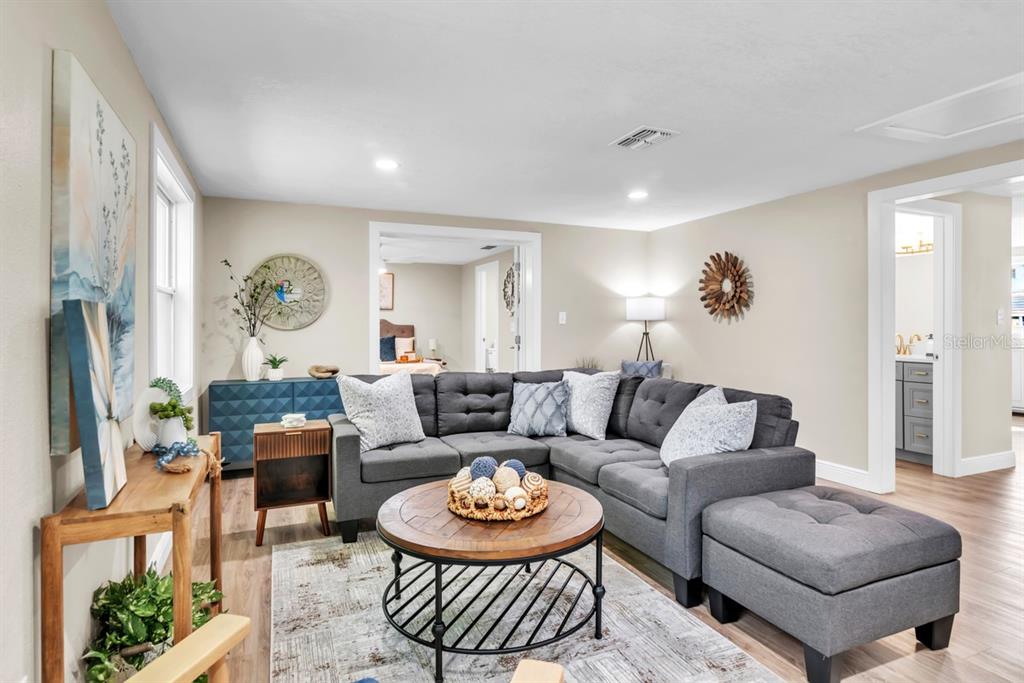 A living room features a gray sectional sofa, a round wooden coffee table, and light flooring — 11416 PINE FOREST DRIVE, NEW PORT RICHEY, FL