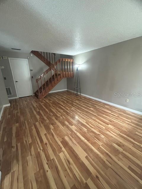An empty room features wood-look flooring, a wooden staircase, and a floor lamp — 4403 PRAIRIE COURT UNIT B, ORLANDO, FL
