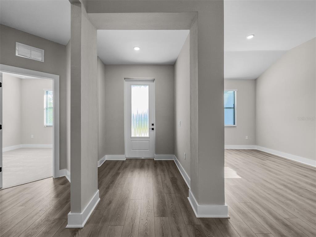 An entryway with light gray walls, wood-look flooring, and a white front door — 5227 DAYTON LANE, PORT CHARLOTTE, FL