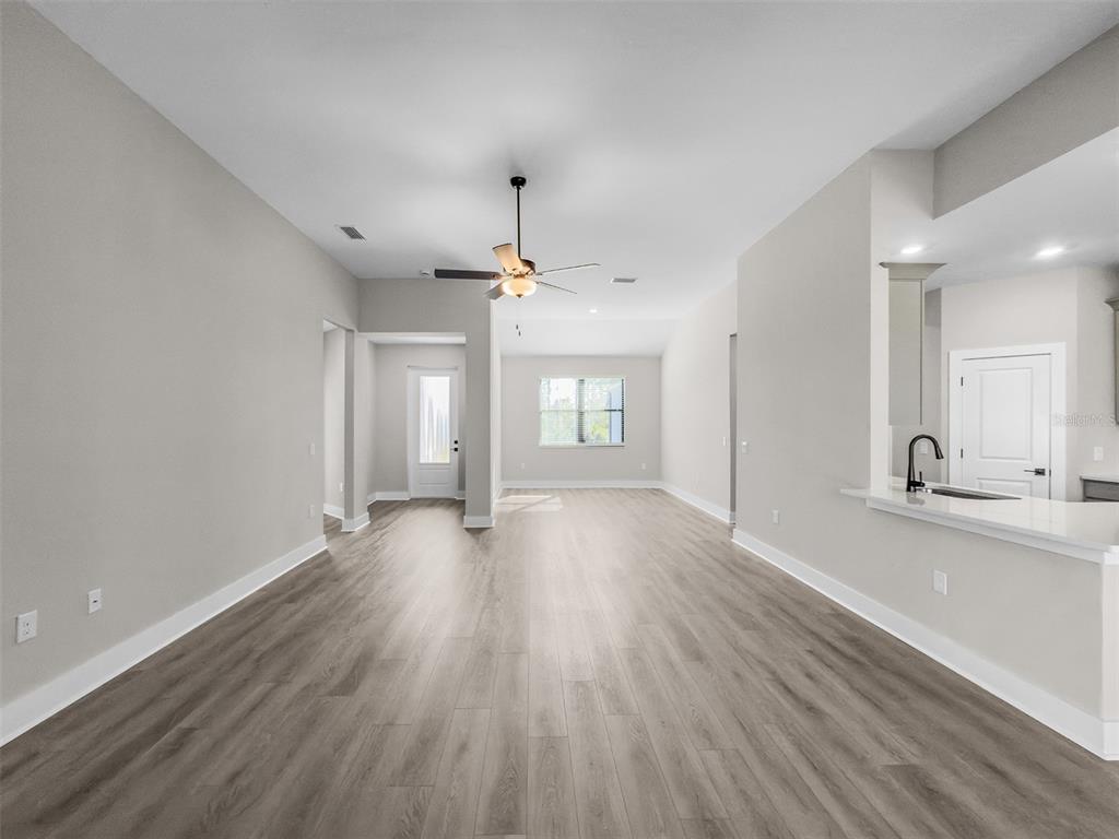 An open-concept living area features light gray walls, wood-look flooring, and a ceiling fan — 5227 DAYTON LANE, PORT CHARLOTTE, FL