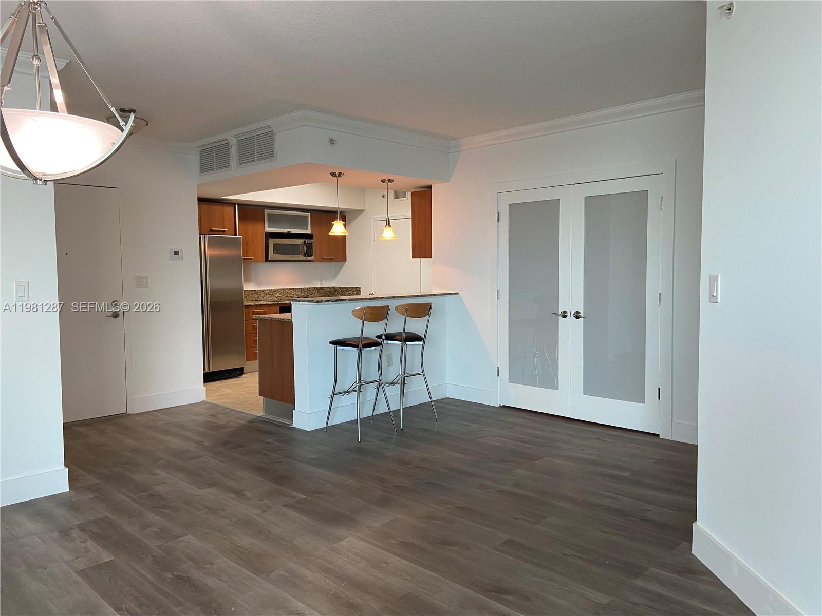 A kitchen with wood cabinets and a breakfast bar opens to a living area — 9055 SW 73rd Ct # 1709, Miami FL 33156, MIAMI, FL