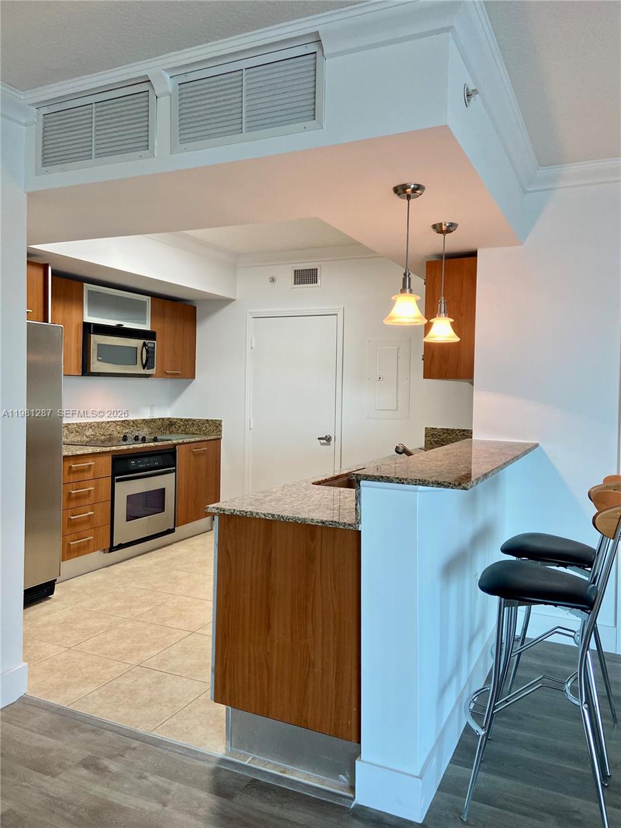A kitchen features wood cabinets, granite countertops, stainless steel appliances, and a breakfast bar — 9055 SW 73rd Ct # 1709, Miami FL 33156, MIAMI, FL