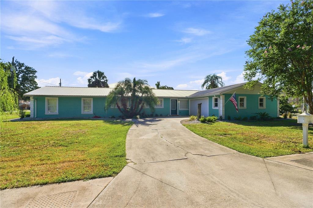 A teal, single-story house with a metal roof and concrete driveway under a blue sky — 1791 NW 21ST COURT, CRYSTAL RIVER, FL