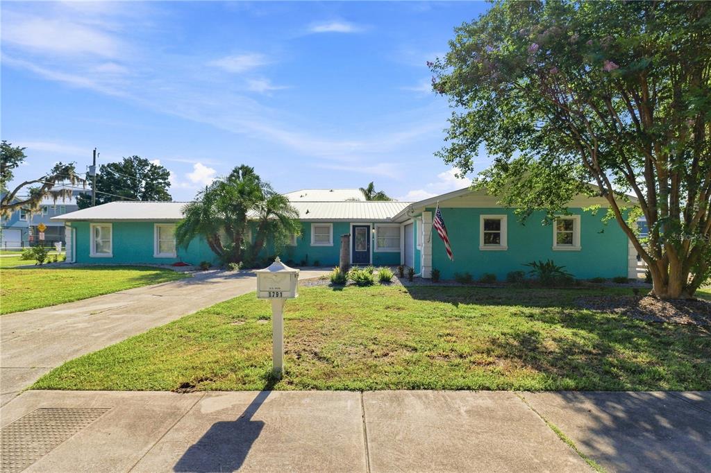 A single-story teal house with a metal roof and a concrete driveway under a blue sky — 1791 NW 21ST COURT, CRYSTAL RIVER, FL
