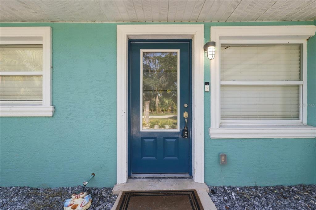 A teal exterior wall features a blue front door with a glass pane and two windows — 1791 NW 21ST COURT, CRYSTAL RIVER, FL