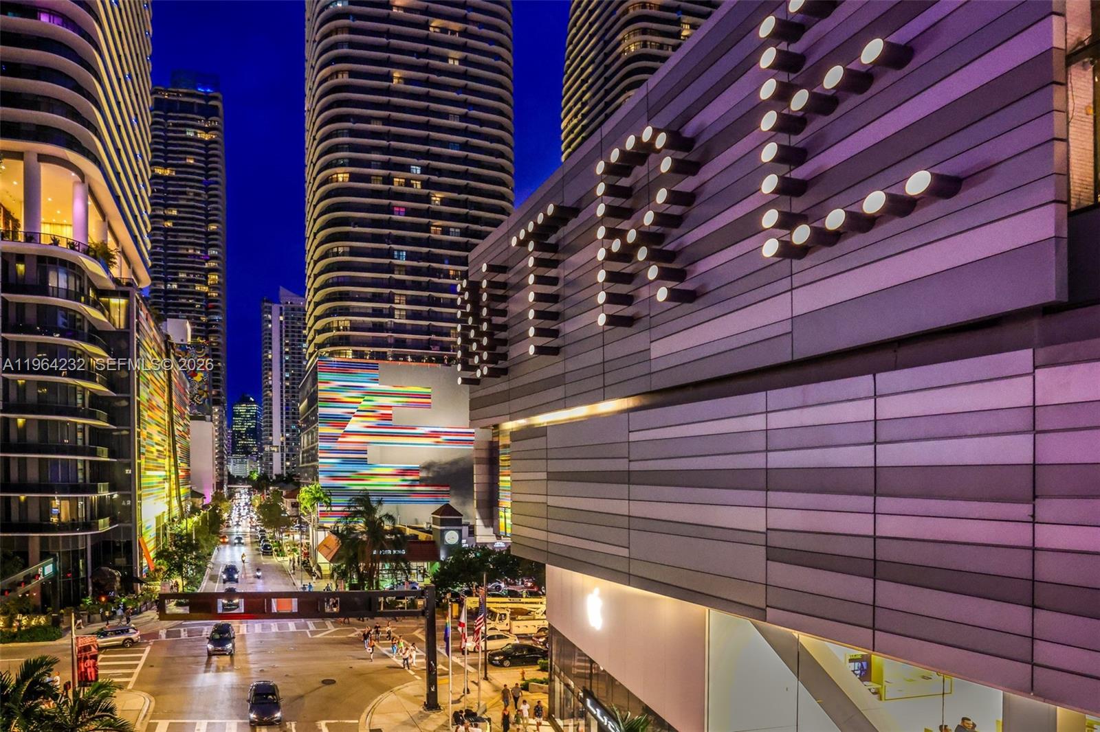An exterior view of a modern city street at night featuring tall buildings and signage — 55 SW 9th St # 3906, Miami FL 33130, MIAMI, FL