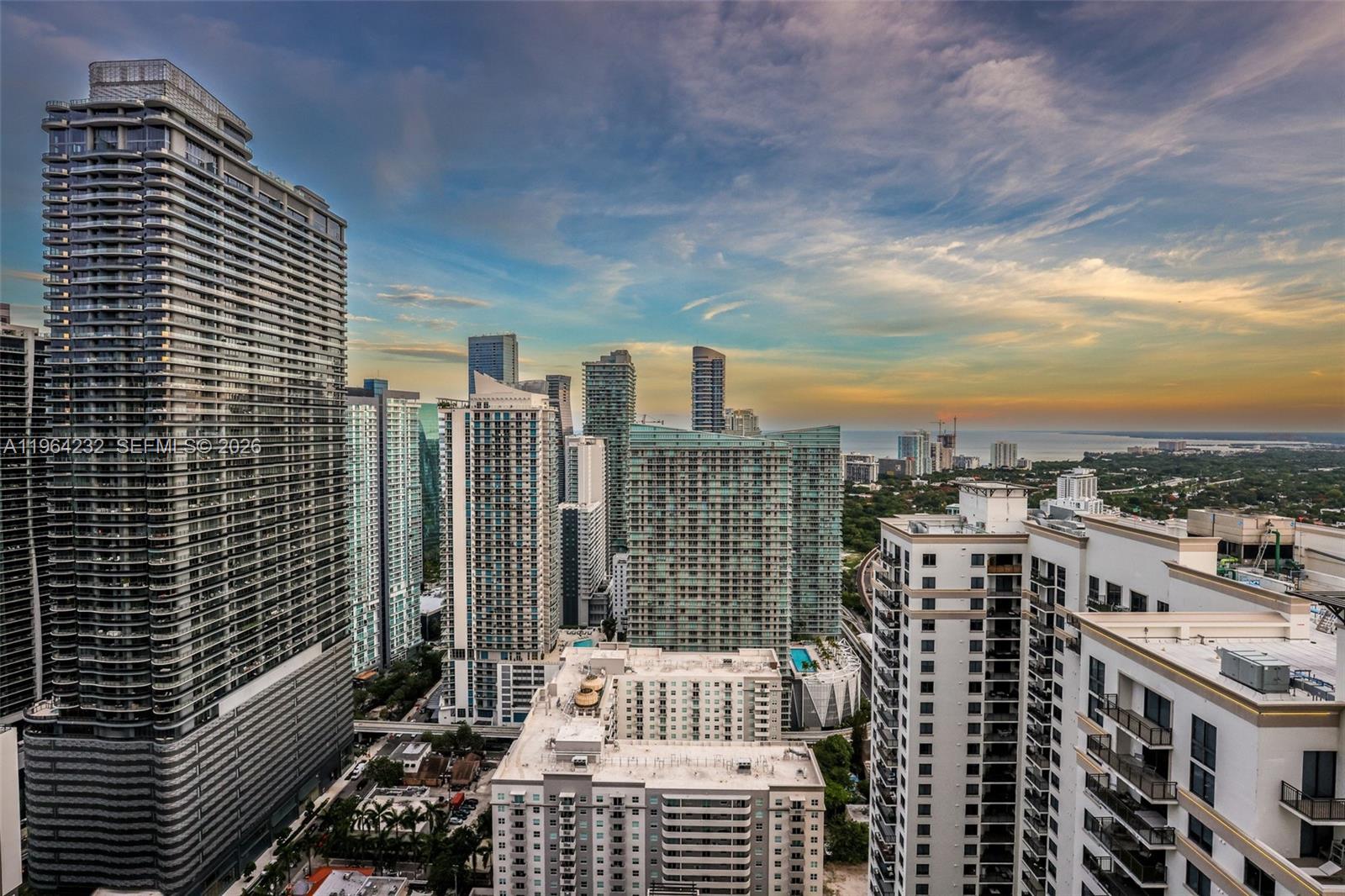 An elevated view of a dense urban skyline featuring numerous high-rise apartment buildings at sunset — 55 SW 9th St # 3906, Miami FL 33130, MIAMI, FL