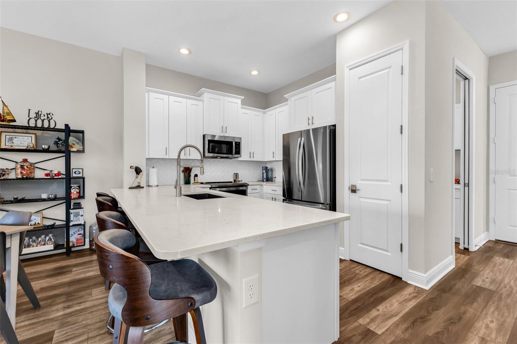A modern kitchen features white cabinetry, stainless steel appliances, and a large quartz-topped island — 24343 WESTGATE BOULEVARD, PUNTA GORDA, FL