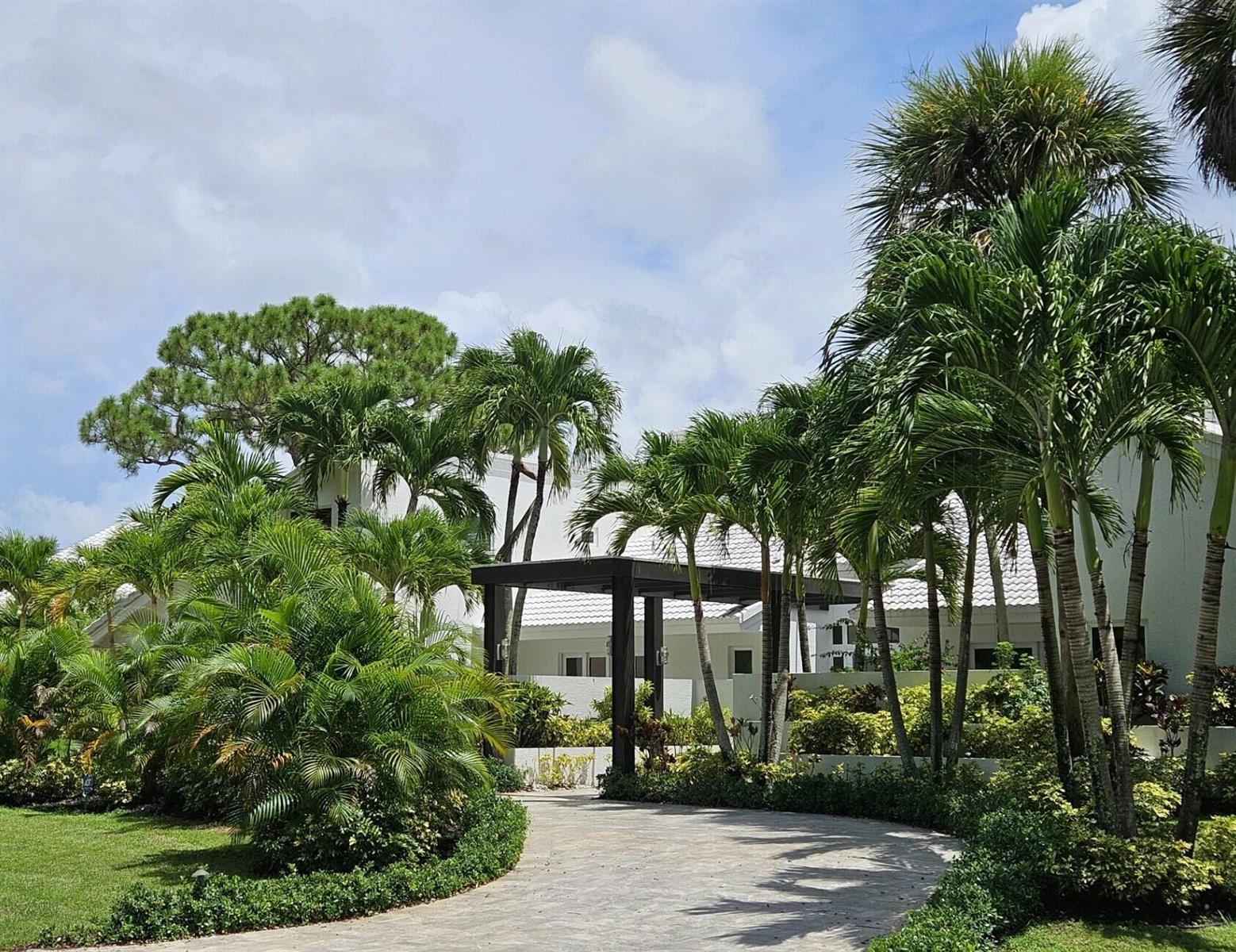 A paved driveway leads to a white house entrance shaded by a modern dark pergola — 355 Oakview Drive, Delray Beach FL 33445, DELRAY BEACH, FL