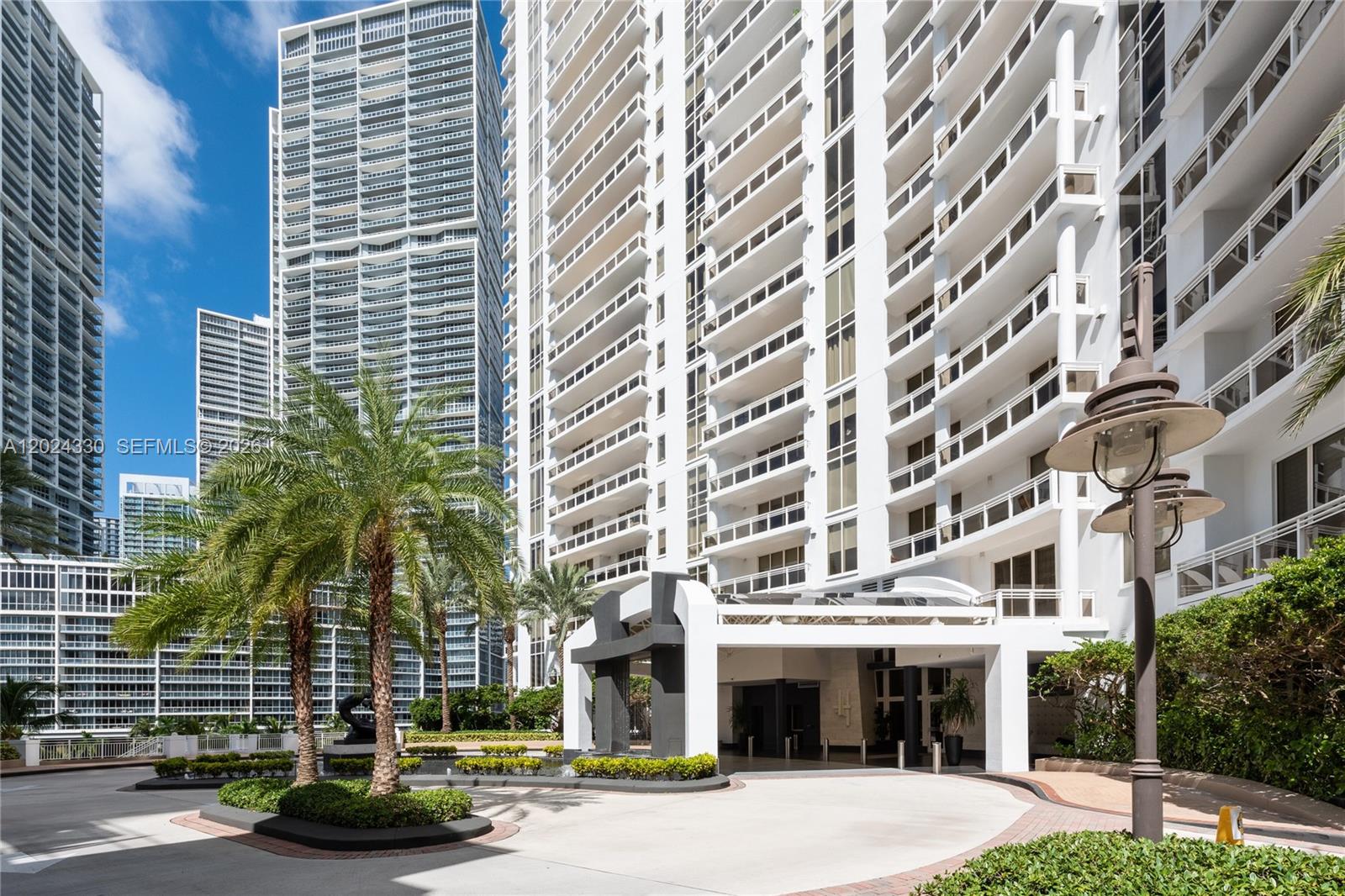 A balcony with stone flooring overlooks a wide bay and a tall residential building — 901 Brickell Key Blvd # 2006, Miami FL 33131, MIAMI, FL