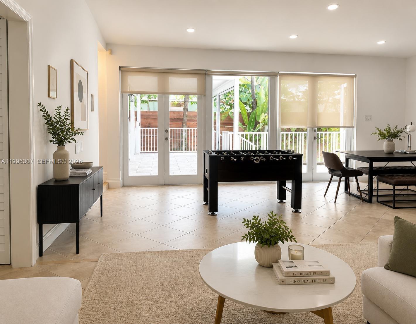 A bright living room features a foosball table, dining area, and glass doors to a patio — 4190 Pamona Ave # 0, Miami FL 33133, MIAMI, FL