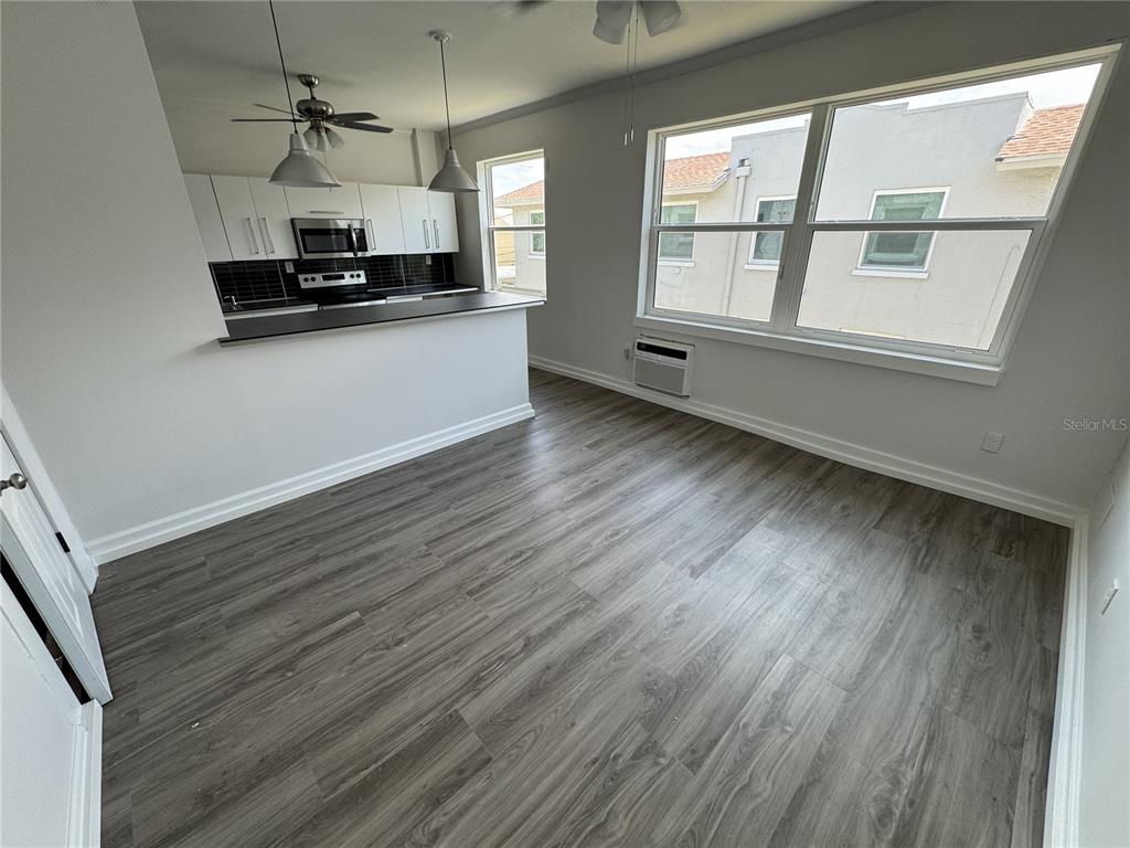 A kitchen with white cabinets and a breakfast bar overlooks a room with wood flooring — 428 ARMADA ROAD S UNIT 6, VENICE, FL
