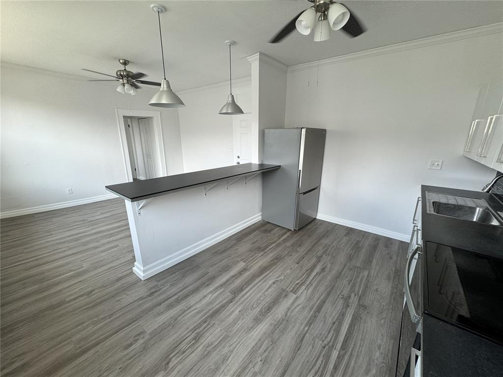 A kitchen with gray wood-look flooring, a breakfast bar, and stainless steel appliances — 428 ARMADA ROAD S UNIT 6, VENICE, FL
