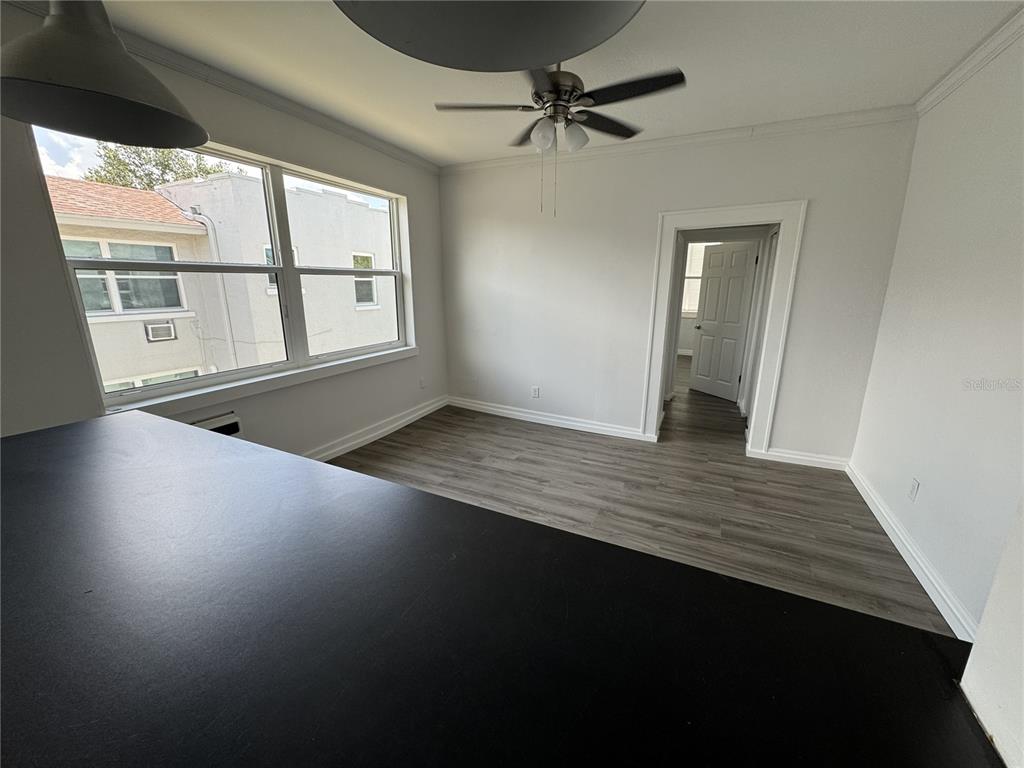 A room with gray wood-look flooring, a ceiling fan, and a view of neighboring buildings — 428 ARMADA ROAD S UNIT 6, VENICE, FL