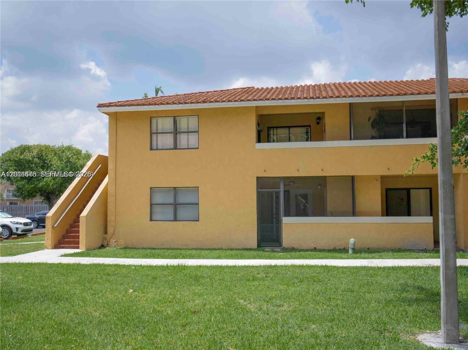 A two-story yellow stucco apartment building features a tiled roof and an exterior staircase — 14831 SW 80th St # 4, Miami FL 33193, MIAMI, FL