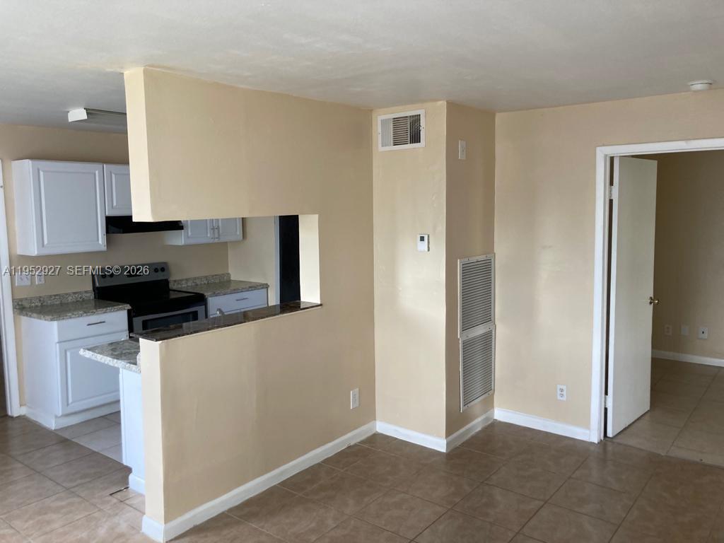 A kitchen with white cabinets and granite countertops opens into a tiled living area — 8705 NW 39th St # 0, Sunrise FL 33351, SUNRISE, FL