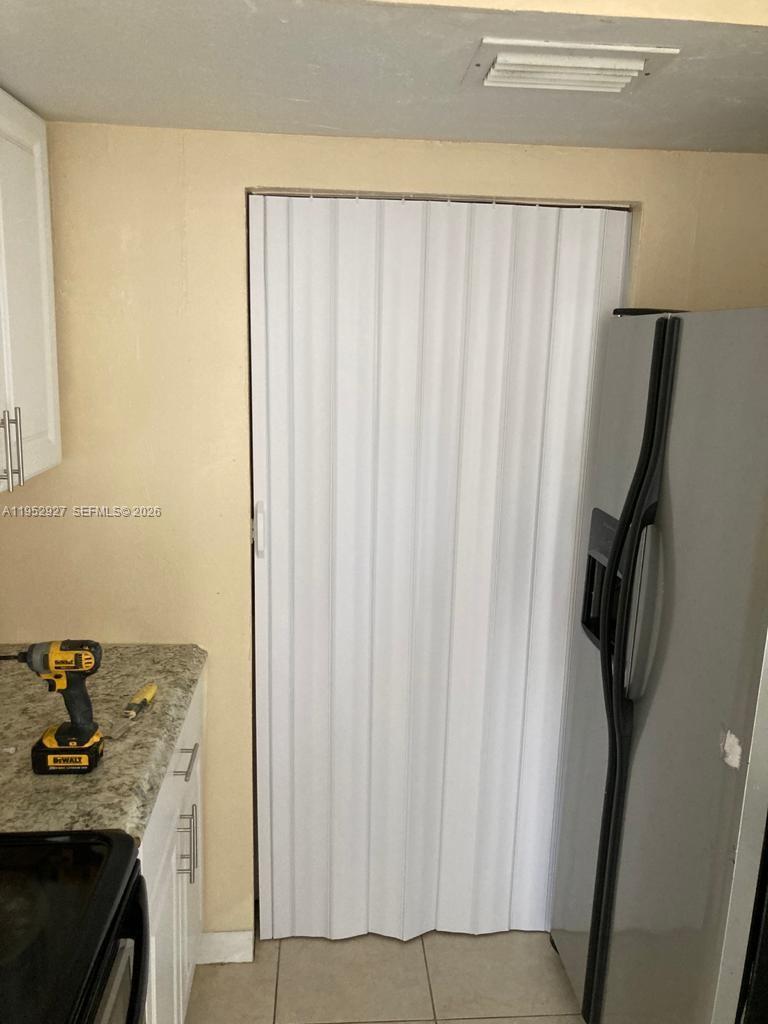 A kitchen features a white accordion door, granite countertops, and a stainless steel refrigerator — 8705 NW 39th St # 0, Sunrise FL 33351, SUNRISE, FL