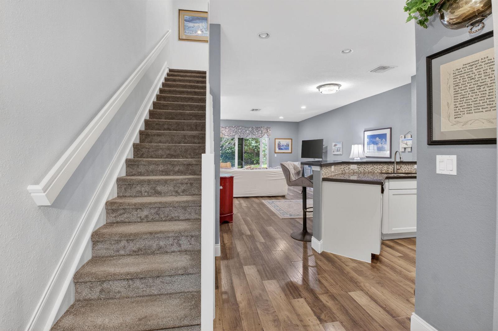 A carpeted staircase leads to an open-concept living area with wood floors and a kitchen — 2626 Webb Avenue, Delray Beach FL 33444, DELRAY BEACH, FL