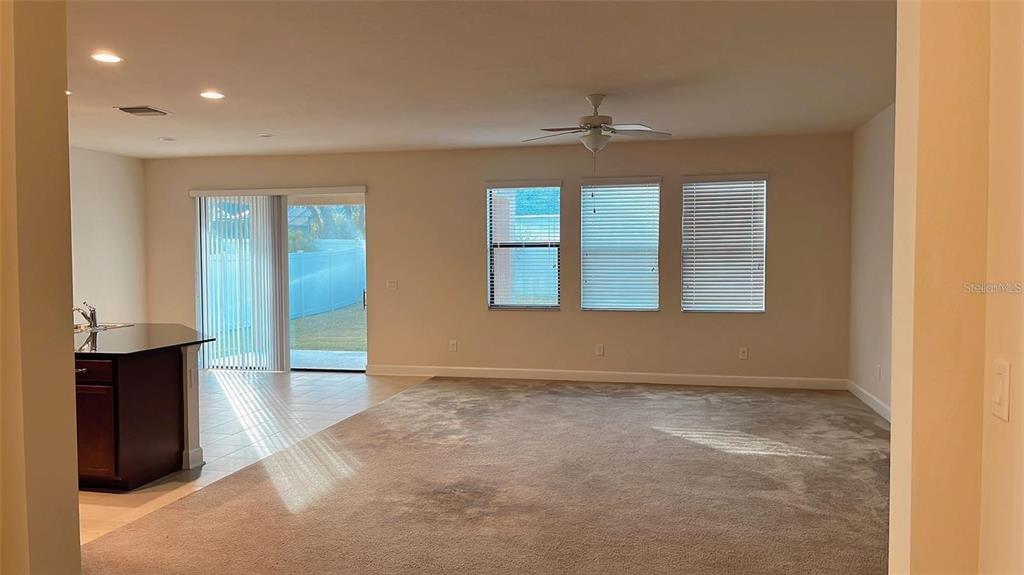 A living room with carpeted flooring, a ceiling fan, and sliding glass doors to a yard — 2931 SHETLAND RIDGE DRIVE, VALRICO, FL