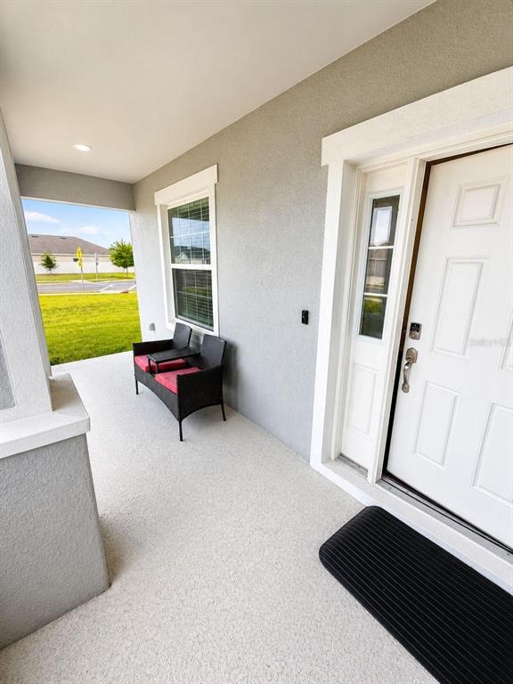 A covered front porch features a small black bench and a white front door — 1032 SILAS STREET, HAINES CITY, FL