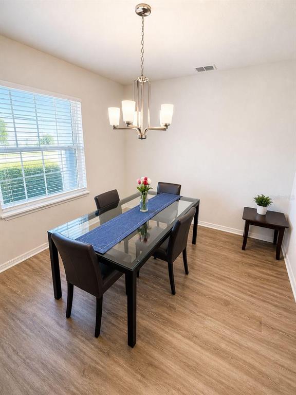 A dining room features a glass-top table, four dark chairs, and a modern chandelier — 1032 SILAS STREET, HAINES CITY, FL