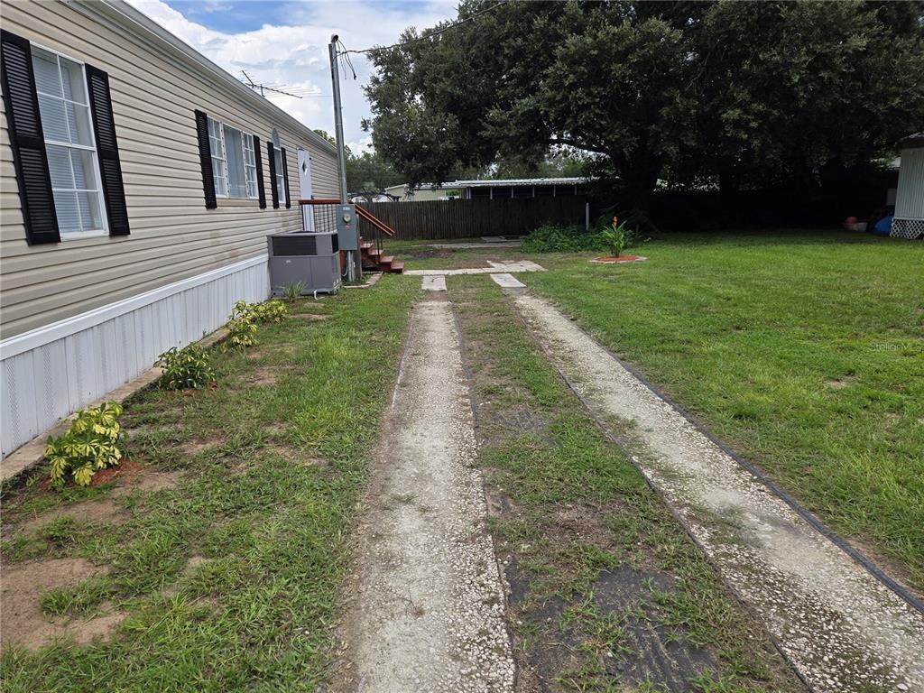 A side view of a mobile home with a concrete strip driveway and grassy yard — 16127 NARROW STREET, BROOKSVILLE, FL