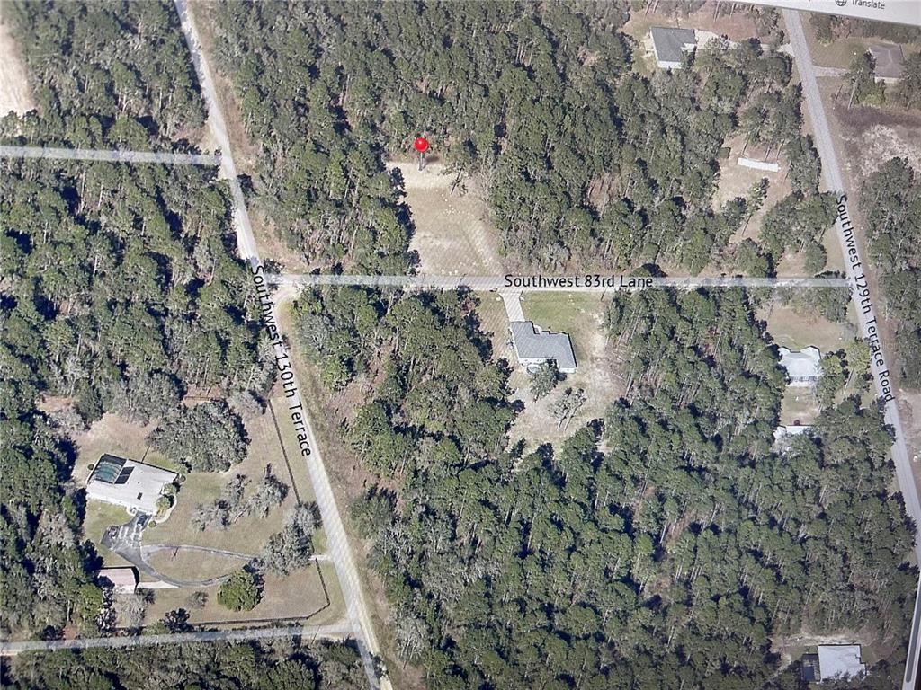 An aerial view shows a wooded residential lot with a red pin marker — 0 SW 83RD STREET, DUNNELLON, FL