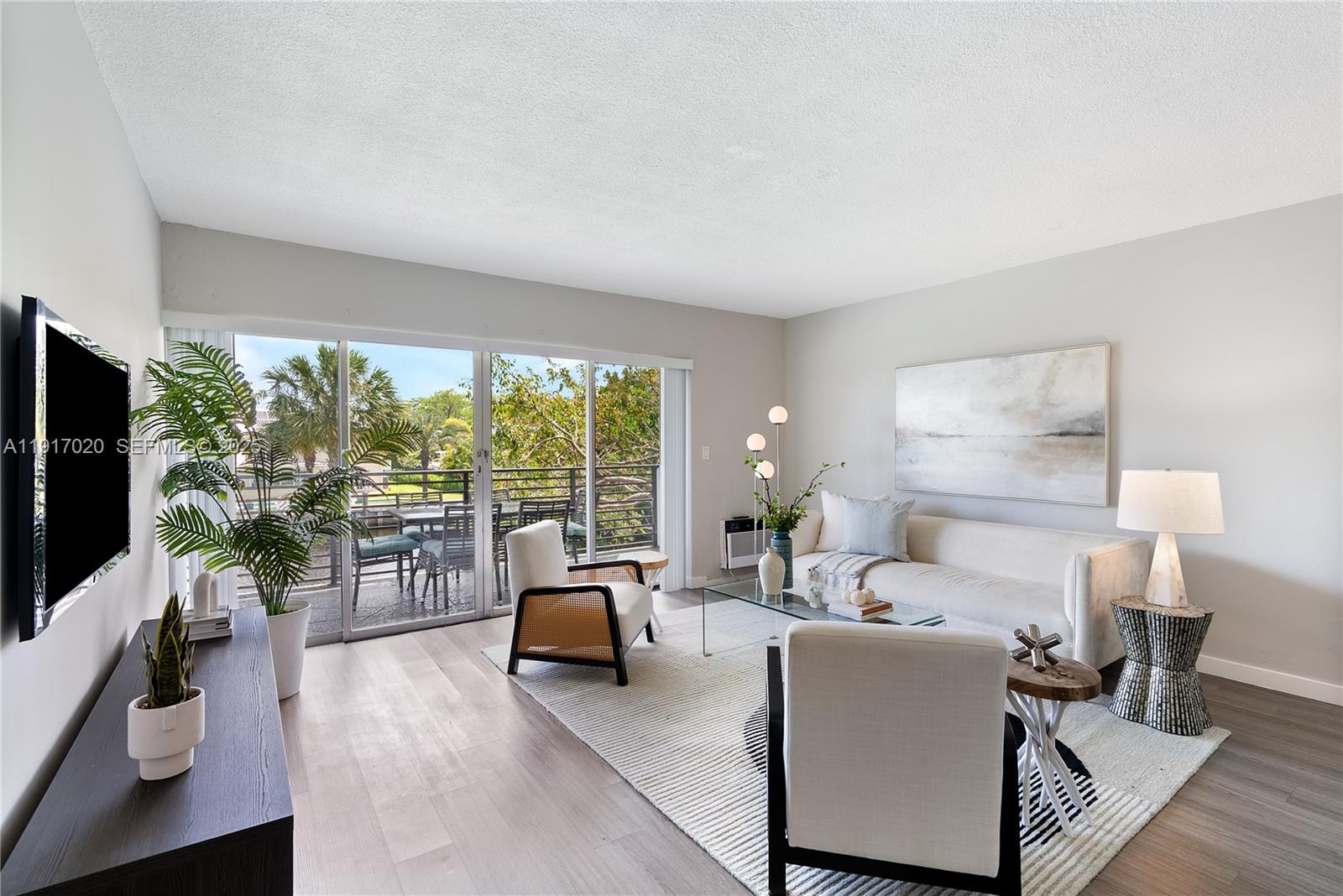 A bright living room features light wood floors, a sofa, two armchairs, and a balcony — 550 NE 20th St # 6, Wilton Manors FL 33305, WILTON MANORS, FL