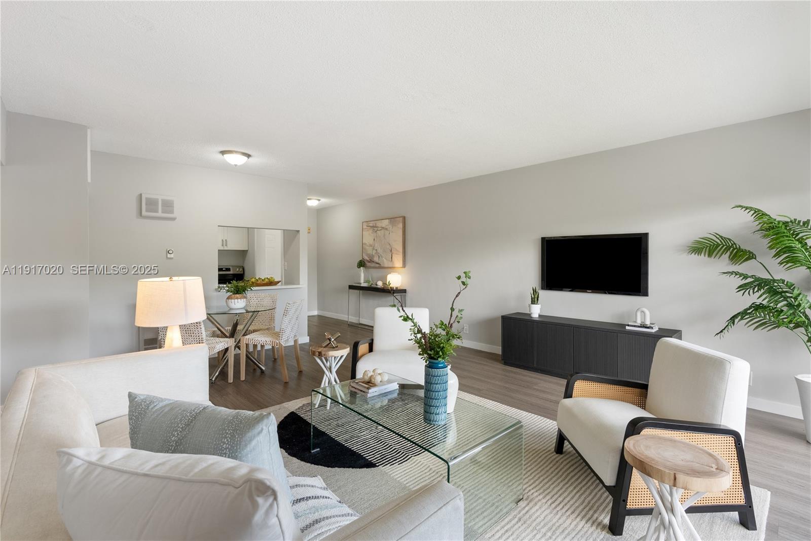 A living room features a glass coffee table, white armchairs, and a wall-mounted television — 550 NE 20th St # 6, Wilton Manors FL 33305, WILTON MANORS, FL