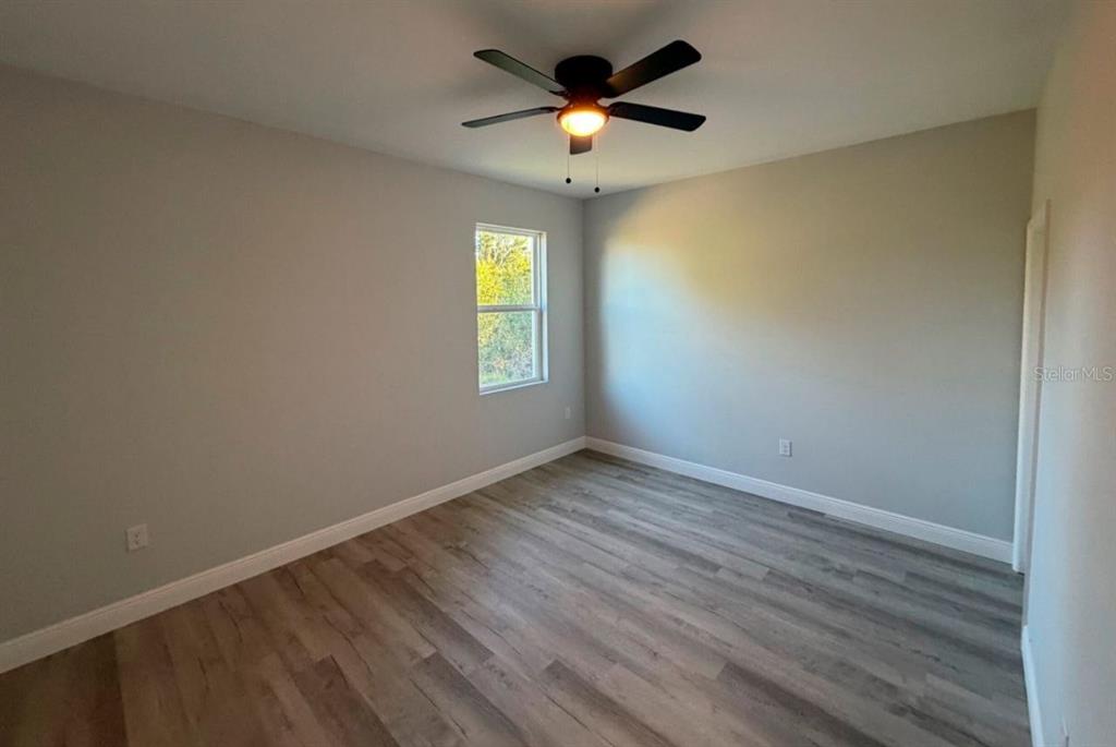 An empty bedroom features light gray walls, wood-look flooring, and a ceiling fan — 2006 E 6TH STREET, LEHIGH ACRES, FL