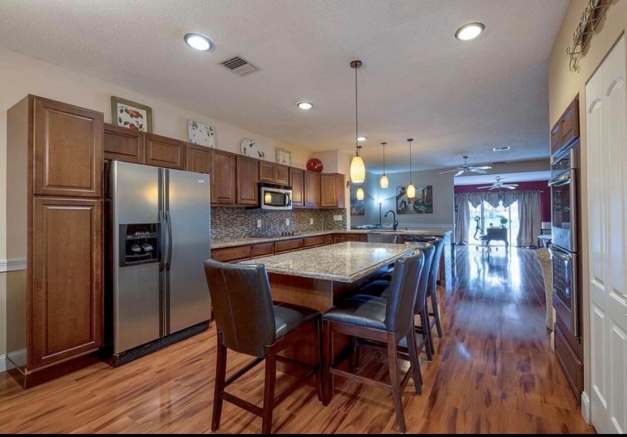 A kitchen with wood cabinets, stainless steel appliances, a granite island, and hardwood flooring — 9217 Boca Gardens Circle S # D, Boca Raton FL 33496, BOCA RATON, FL
