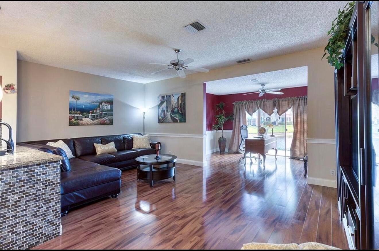 A living room with dark leather sectional seating, wood flooring, and an adjacent office area — 9217 Boca Gardens Circle S # D, Boca Raton FL 33496, BOCA RATON, FL