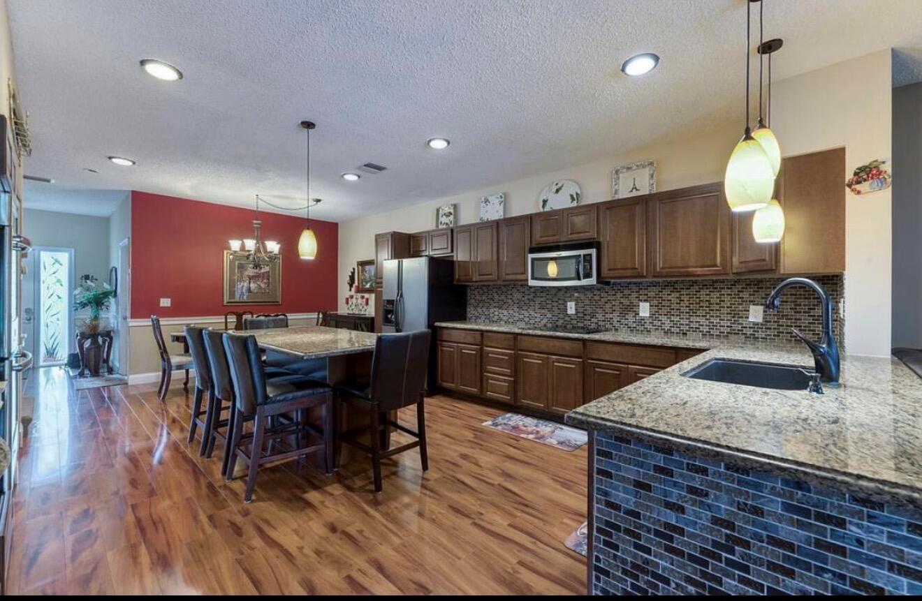 A kitchen with dark wood cabinets, granite countertops, and a dining area with red walls — 9217 Boca Gardens Circle S # D, Boca Raton FL 33496, BOCA RATON, FL