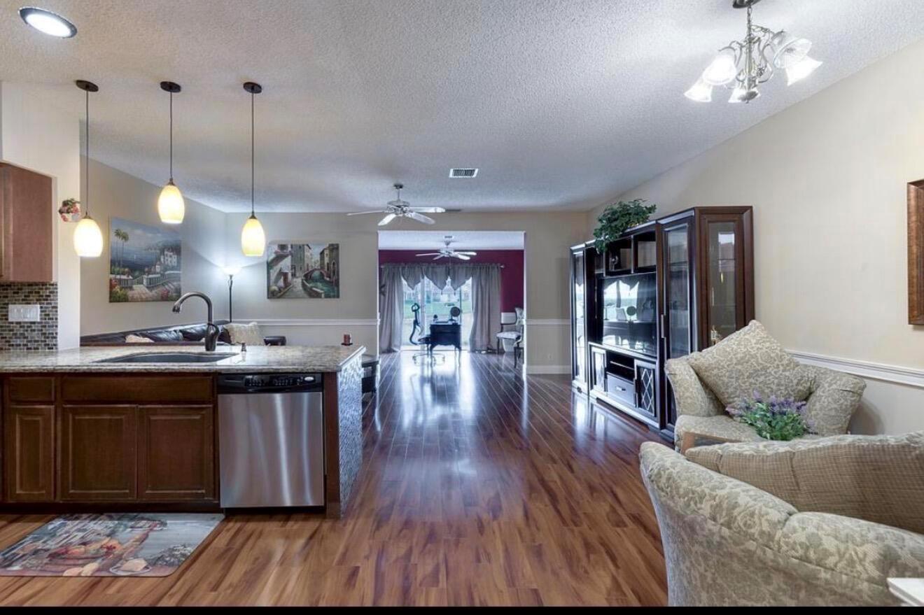 A kitchen island with a stainless steel dishwasher overlooks a living area with wood flooring — 9217 Boca Gardens Circle S # D, Boca Raton FL 33496, BOCA RATON, FL