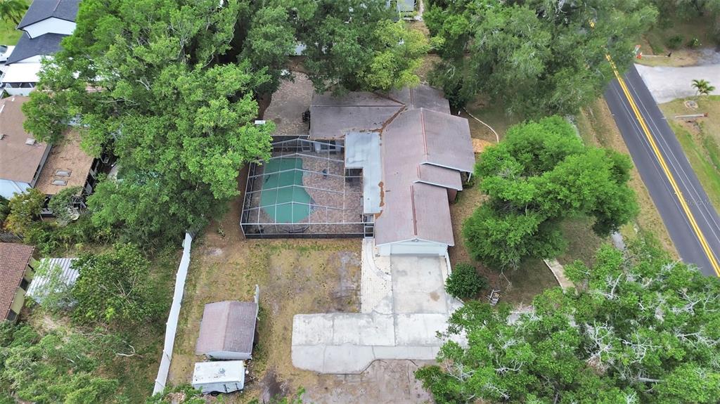 An aerial view shows a house with a screened-in pool, driveway, and surrounding trees — 7608 BARRY ROAD, TAMPA, FL