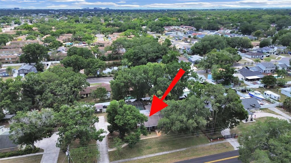 An aerial view shows a single-story house surrounded by mature trees and a paved driveway — 7608 BARRY ROAD, TAMPA, FL