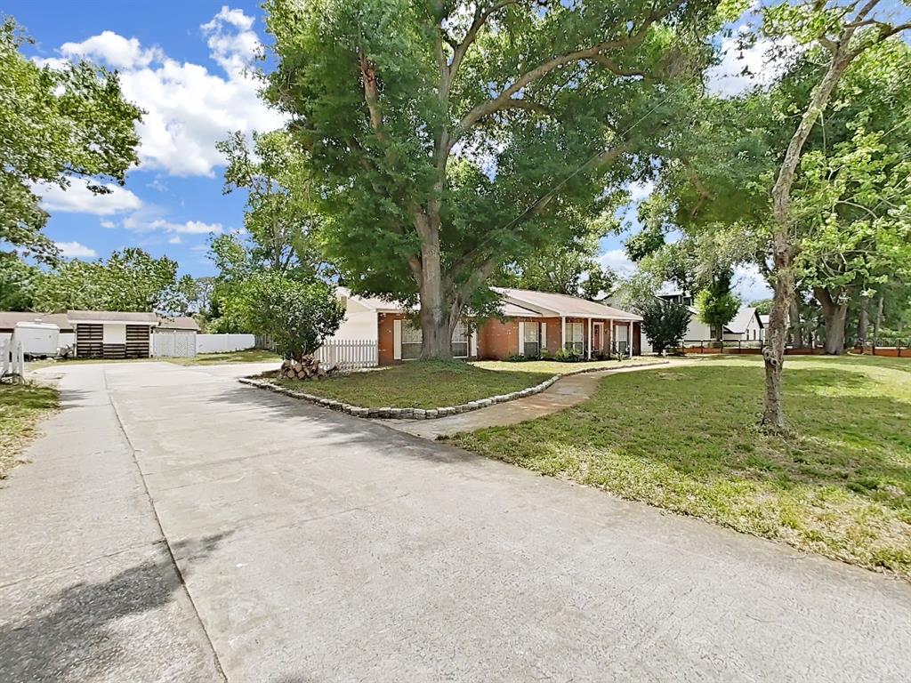 A single-story brick house with a large front yard and a concrete driveway — 7608 BARRY ROAD, TAMPA, FL