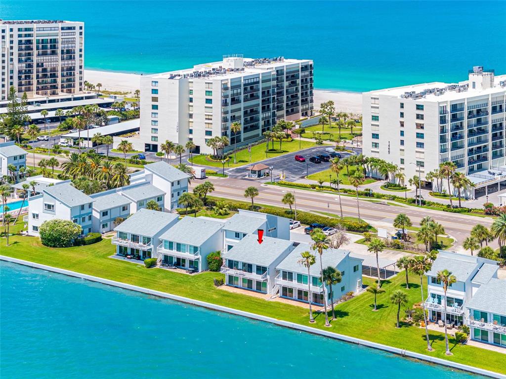 An aerial view of a waterfront condominium complex with a red arrow pointing to a unit — 1401 GULF BOULEVARD UNIT 212, CLEARWATER BEACH, FL