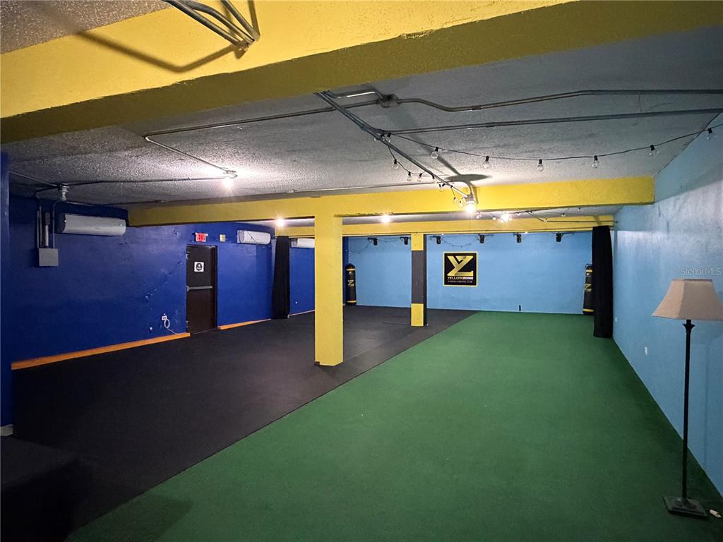 A gym space features blue walls, yellow support columns, black rubber flooring, and green turf — 158 CALLE PROGRESO, AGUADILLA, PR