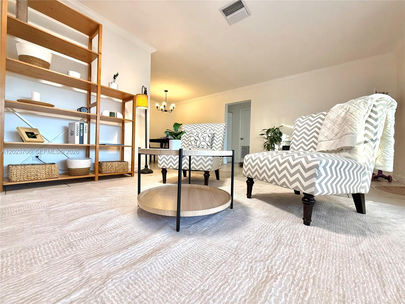 A living room features a wooden shelving unit, two chevron-patterned chairs, and a round table — 232 SE 6th St, Dania Beach FL 33004, DANIA BEACH, FL