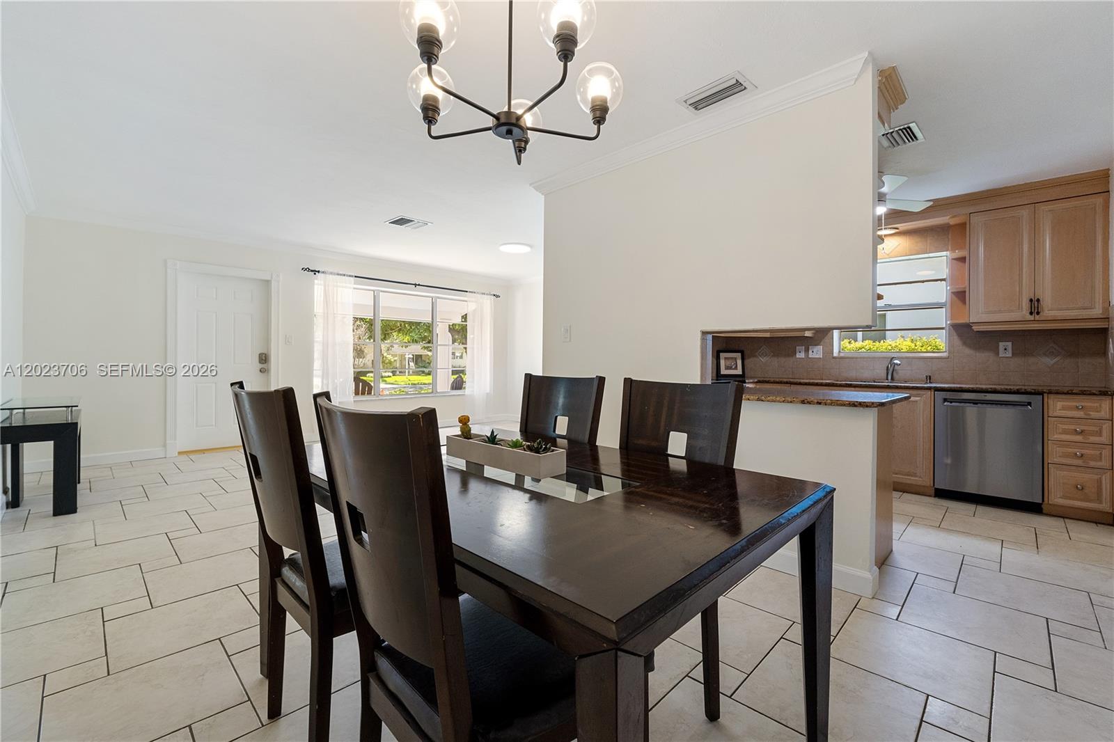 A dining area with a dark wood table and chairs sits adjacent to a kitchen — 232 SE 6th St, Dania Beach FL 33004, DANIA BEACH, FL