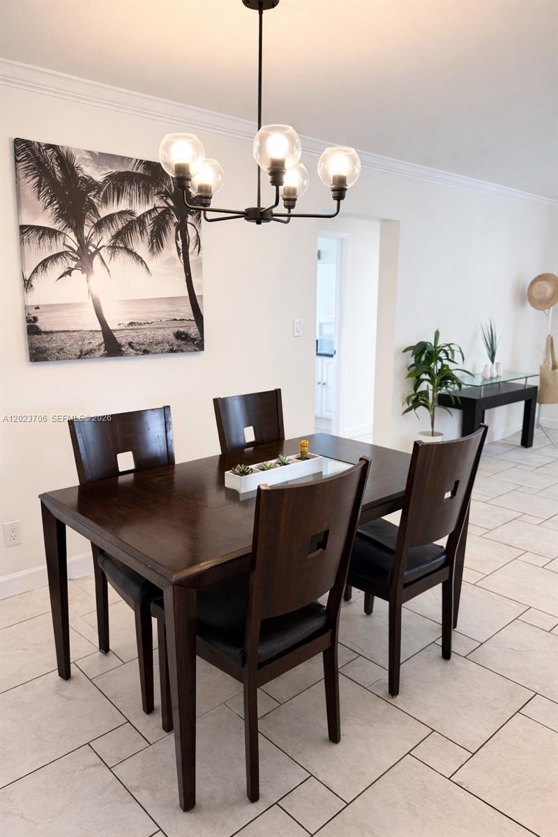 A dining room features a dark wood table and chairs under a modern chandelier — 232 SE 6th St, Dania Beach FL 33004, DANIA BEACH, FL