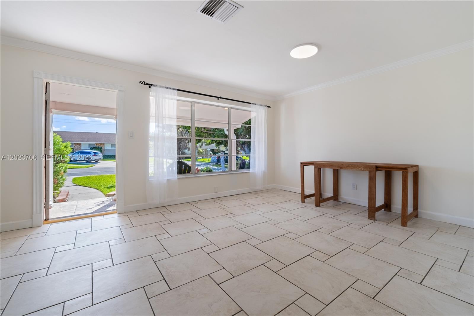 A bright room features light-colored tile flooring, a large window, and an open doorway — 232 SE 6th St, Dania Beach FL 33004, DANIA BEACH, FL