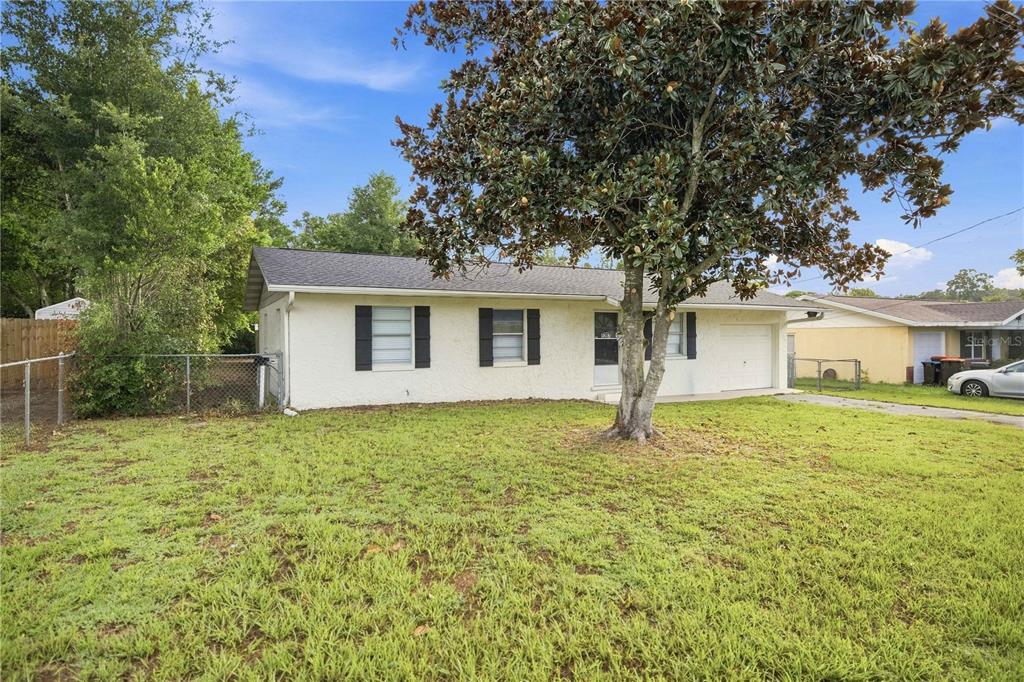 A single-story house with white stucco walls, black shutters, and a front yard tree — 5207 SE 107TH PLACE, BELLEVIEW, FL