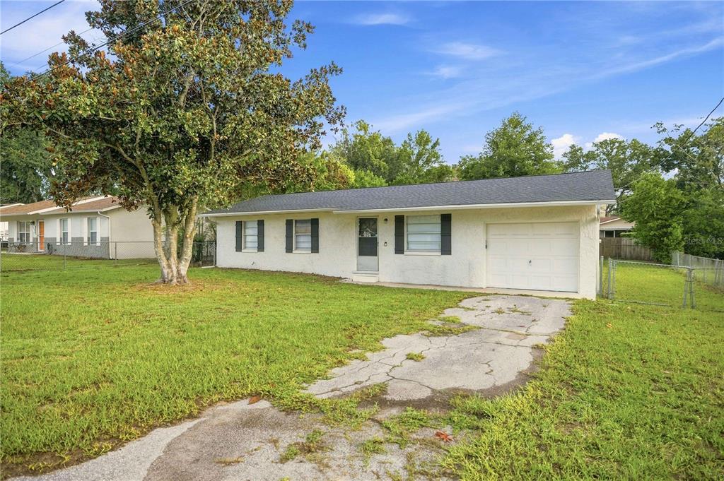 A single-story white house with a garage and a large tree in the front yard — 5207 SE 107TH PLACE, BELLEVIEW, FL