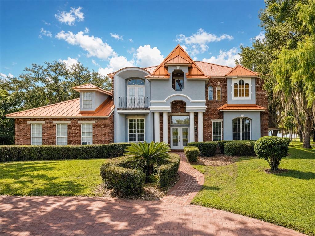 A two-story house with a brick and stucco exterior and a copper-colored metal roof — 10550 LAKE MINNEOLA SHORES, CLERMONT, FL