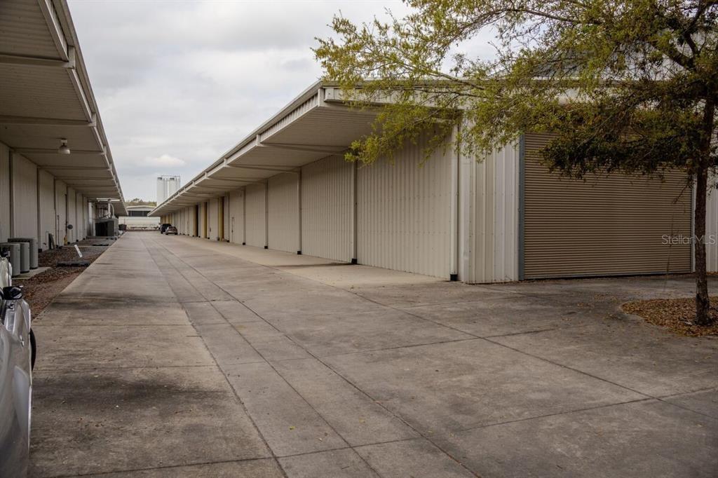 A concrete driveway runs between two long, metal-sided storage buildings with roll-up doors — 2251 TOPLINE WAY UNIT 2, BROOKSVILLE, FL